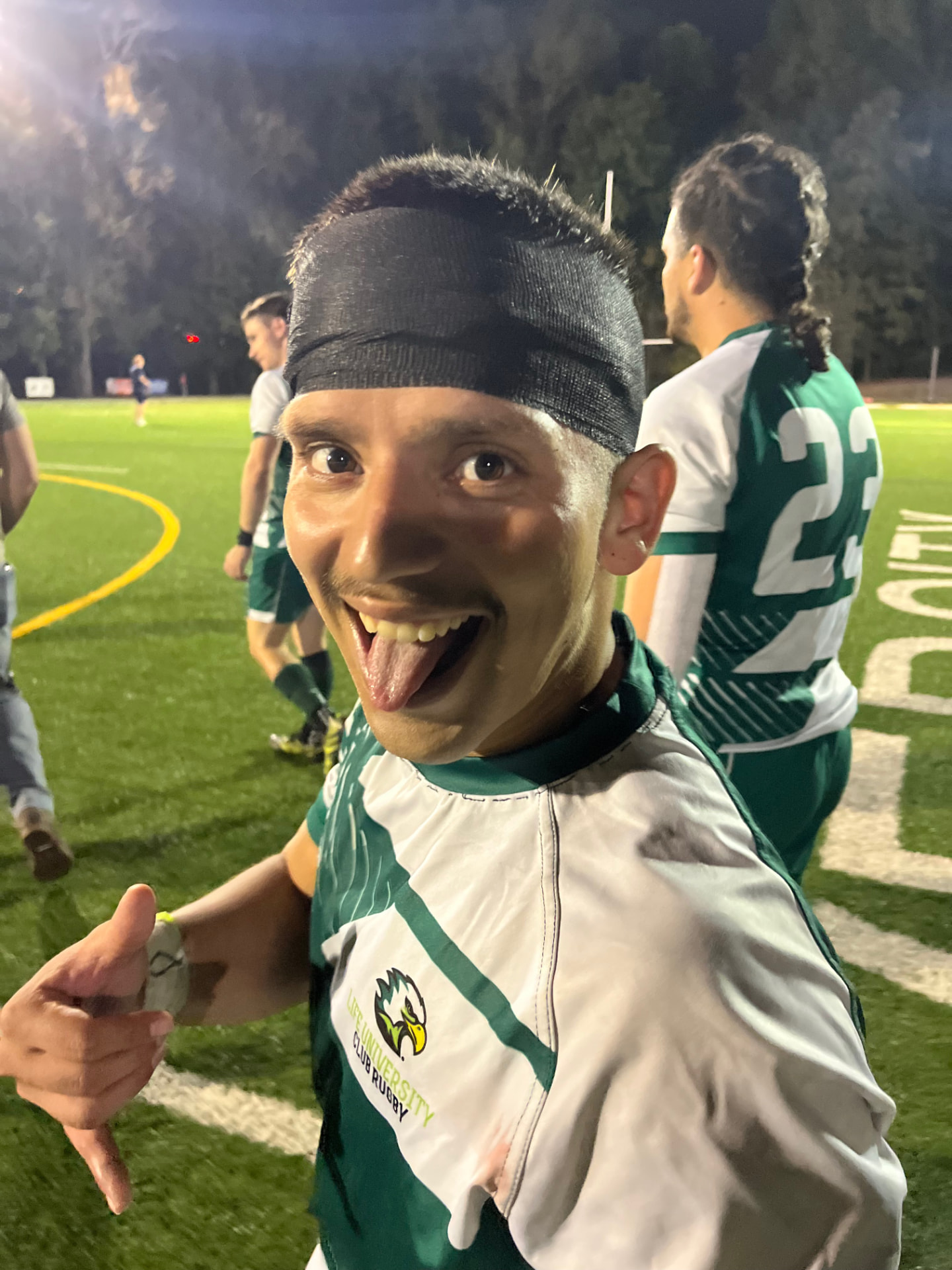 Dr. Adrian Escobedo smiling on the rugby field during a night game